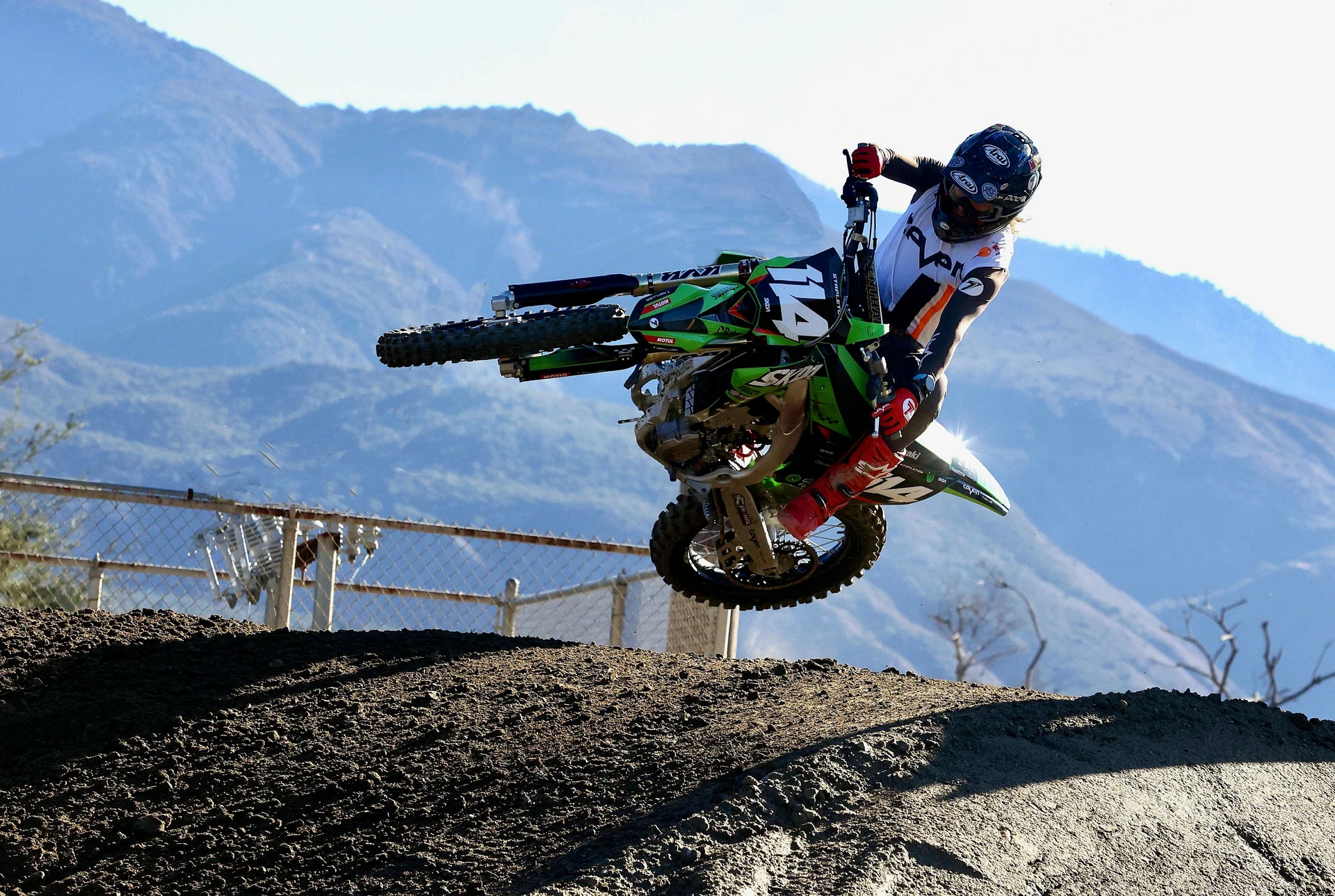 Geran Stapleton riding his green motocross bike against the California mountains